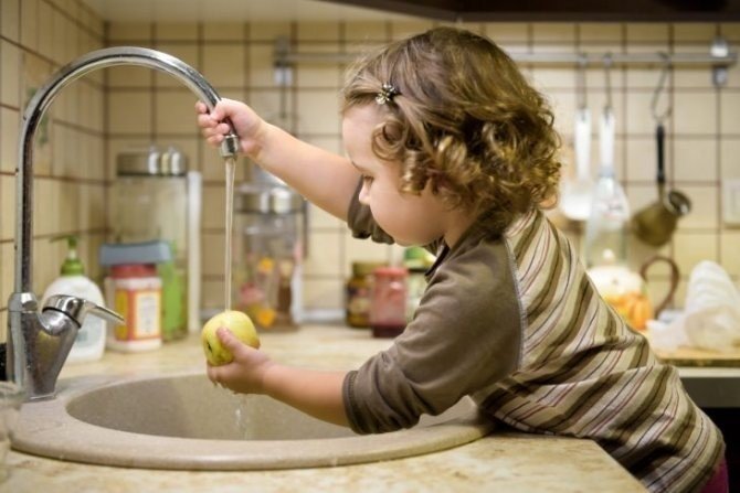 Маленькая девочка моет посуду